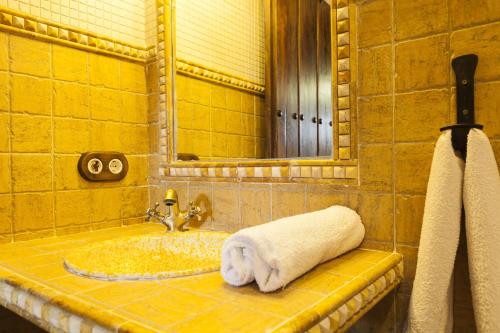 Baño con una toalla sobre un lavabo en Cortijo La Algallumbilla, en Carcabuey