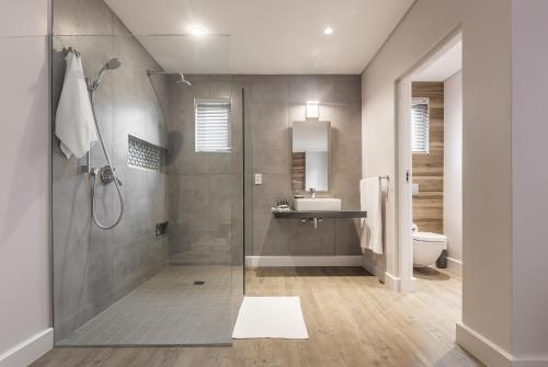 a bathroom with a shower and a sink and a toilet at The Junction Boutique Hotel in Plettenberg Bay