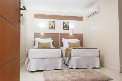 two beds in a bedroom with white walls at Hotel Cravo e Canela in Campos dos Goytacazes