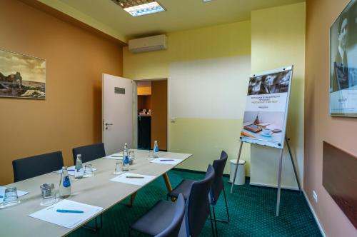 a conference room with tables and chairs and a screen at Mercure Czestochowa Centrum in Częstochowa