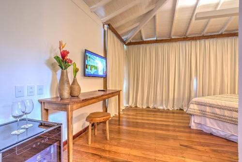 a bedroom with a bed and a table with flowers on it at A Casa de Gabriella in Itacaré