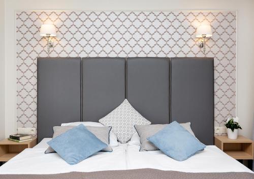 um quarto com uma cama branca e almofadas azuis em Villa Grand Solis em Świnoujście