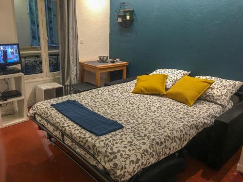 um quarto com uma cama com duas almofadas amarelas em Studio vieil Antibes em Antibes