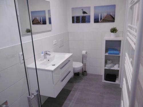 ein weißes Bad mit einem Waschbecken und einem WC in der Unterkunft Ferienwohnung Wiesenblick nahe Region Celle und Hannover in Buchholz (Aller)
