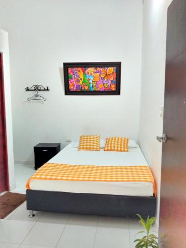 a bedroom with a bed with a painting on the wall at Hotel Nicole in Girardot