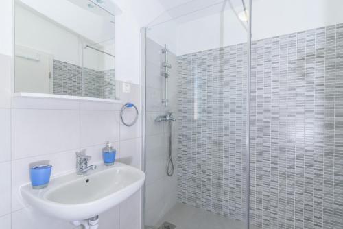 uma casa de banho branca com um lavatório e um chuveiro em Apartments Beba - peaceful location em Trogir