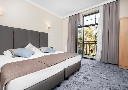 a bedroom with a large bed and a large window at Villa Grand Solis in Świnoujście