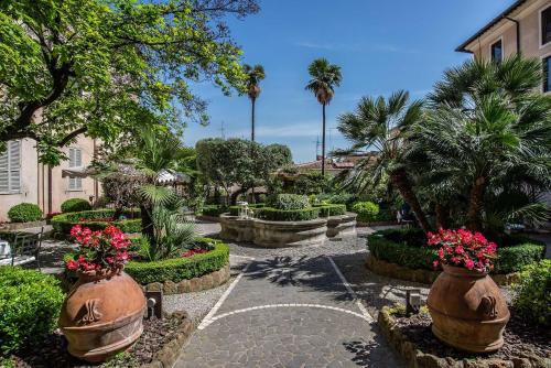 a garden with flowers in large vases and palm trees at Donna Camilla Savelli - VRetreats in Rome