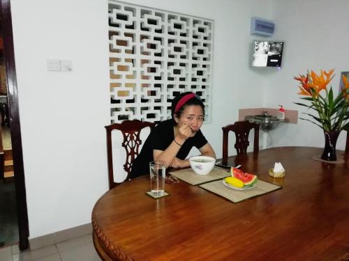 a woman sitting at a table with a bowl of watermelon at Old Parkland Hostel in Galle