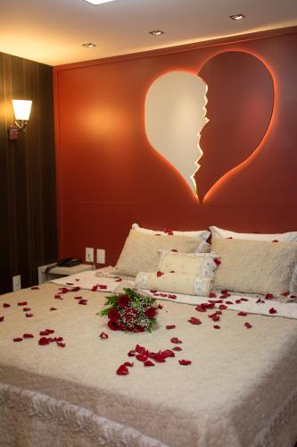a bed with roses on it with a heart on the wall at Hotel Cravo e Canela in Campos dos Goytacazes
