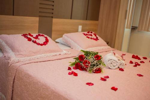 a pink bed with red roses and hearts on it at Hotel Cravo e Canela in Campos dos Goytacazes
