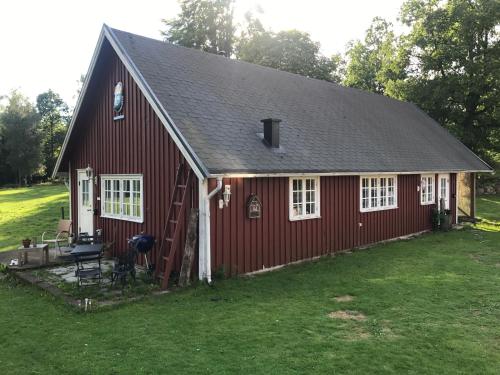 a red barn with a ladder and a grill at Sävekulla 207 "Brygghuset" in Älvsered