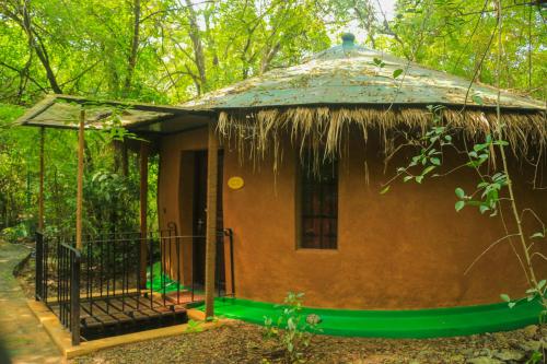 a small hut with a thatched roof in a forest at Akein Jungle Resort - Sigiriya in Sigiriya