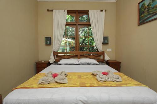 a bed with two towels on it with a window at Villa Rama in Candidasa