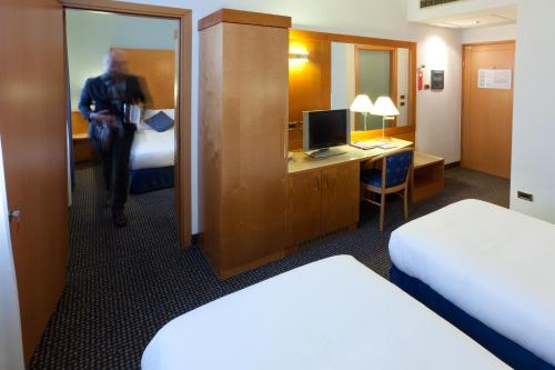 a man walking into a hotel room with a bedroom at UNA HOTELS Occhiobello in Occhiobello