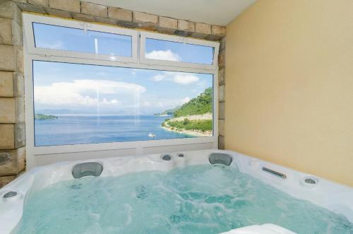 a bath tub in a room with a large window at Adriatic - Apartment with jacuzzi in Sobra