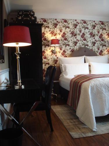 a bedroom with a bed and a desk with a lamp at Hotel Sir & Lady Astor in Düsseldorf