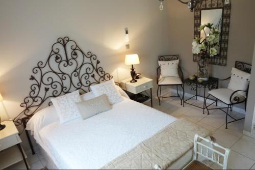 a bedroom with a large white bed and two chairs at Chez Virginie in Porto-Vecchio