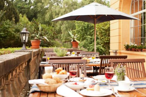 a table with food and wine glasses and an umbrella at Schlosshotel Ziethen in Kremmen