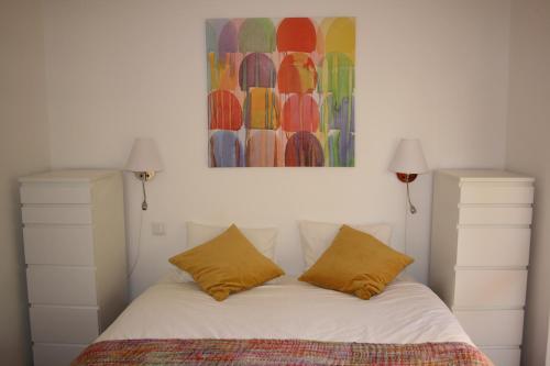 a bed with two pillows and a painting above it at Seastar in Vilamoura