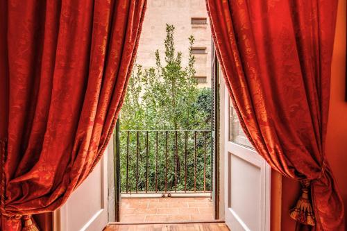 an open window with red curtains and a balcony at Elegant Flat by the Vatican dx in Rome