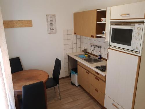 eine kleine Küche mit einem Tisch und einem weißen Kühlschrank in der Unterkunft AB Apartment Objekt 24 in Stuttgart