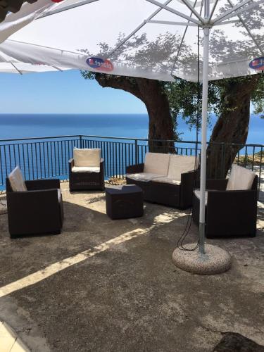 a patio with chairs and an umbrella and a tree at Residenze Cutrì Casa Vacanze Cilento by ElodeaGroup in Pisciotta