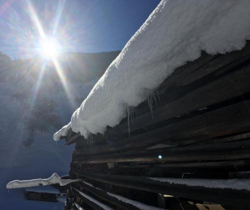 a roof covered in snow with the sun behind it at Haus Ladner in See