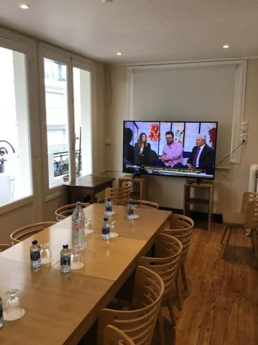 Pokój ze stołami i telewizorem z płaskim ekranem w obiekcie Grand Hôtel de la Poste w mieście Saint-Jean-de-Luz