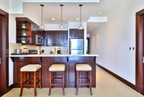 a kitchen with wooden cabinets and a counter with stools at 360 Splendor Del Pacifico Residences in Playa Flamingo