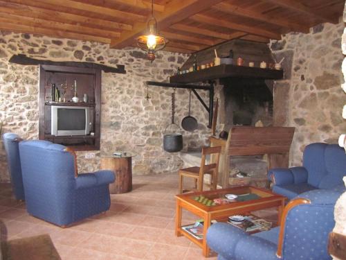 a living room with blue chairs and a stone fireplace at Casa Os Carballás in Merille