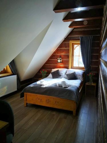 une chambre avec un grand lit dans un grenier dans l'établissement Domek u Kubusia, à Białka Tatrzańska