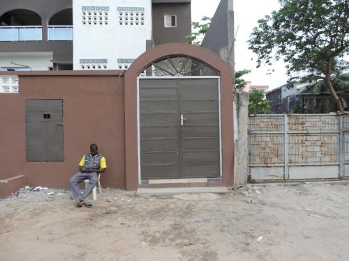a man sitting in a chair in front of a garage at Happy Welcome Bietry in Abidjan