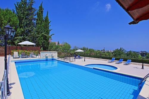 a large swimming pool with blue chairs at Villa Mandola Rosa in Prodhromi