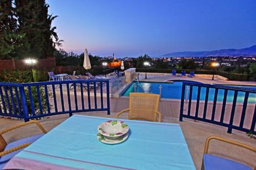 a blue table and chairs on a patio with a pool at Villa Mandola Rosa in Prodhromi