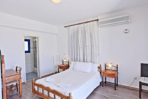 a bedroom with a bed and two tables and a window at Villa Mandola Rosa in Prodhromi