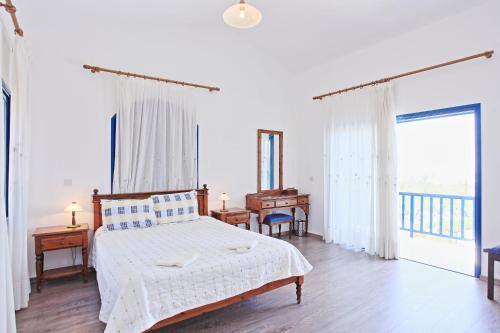 a white bedroom with a bed and a balcony at Villa Mandola Rosa in Prodhromi