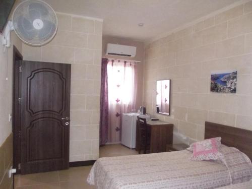 a bedroom with a bed and a sink and a window at Sunset Seaview Accommodation in Marsalforn
