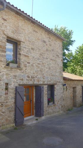 une maison en pierre avec une porte orange et des fenêtres dans l'établissement Gîte de la Vallée, à Saint-Jean-de-Boiseau