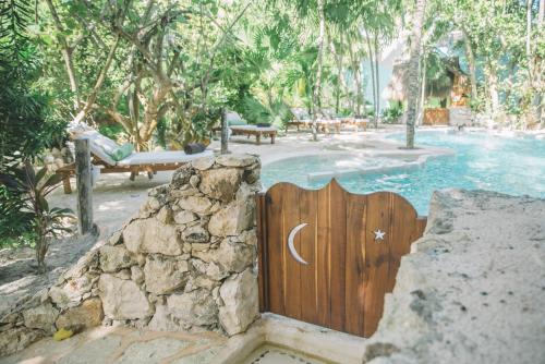 a wooden gate to a swimming pool with a crescentresent at Cabañas La Luna in Tulum