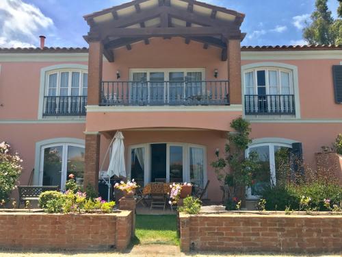 a large pink house with a balcony at Depto Quintay, cómodo y a pasos de la playa in Quintay