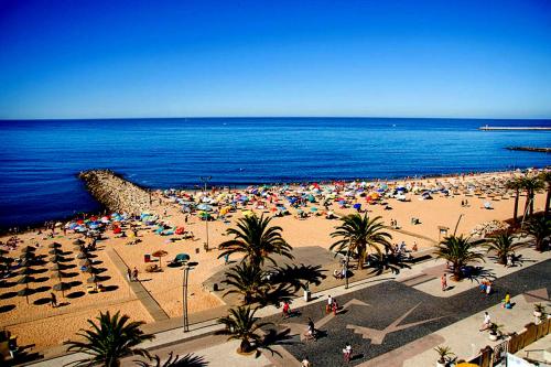 a beach with a lot of people and the ocean at Quarteira Beach in Quarteira