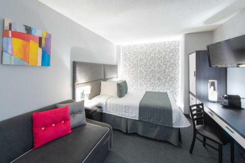 a hotel room with a bed and a couch and a desk at Travelodge by Wyndham Montreal Centre in Montréal