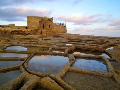 a building on top of a hill with some water at Sunset Seaview Accommodation in Marsalforn