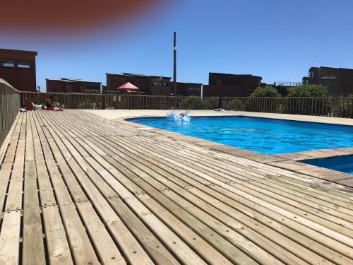 a wooden deck next to a swimming pool at Condominio Privado a Pasos del Mar in Pichilemu