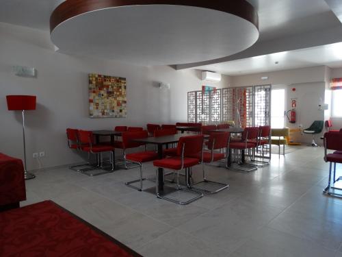 a dining room with red chairs and a table at Aires da Serra Hotel in Torres Novas