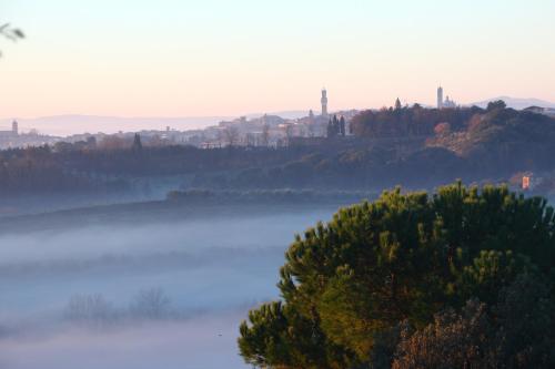 a misty lake with a city in the background at CasaLeTolfe Residence in Siena