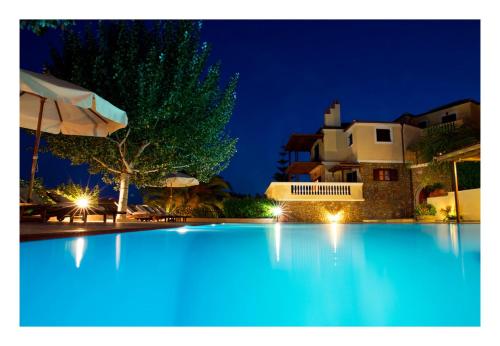 a large swimming pool at night with a house at Alonissos beach villa 5 steps away from the sea in Kalamakia