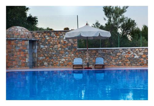 two chairs and an umbrella next to a swimming pool at Alonissos beach villa 5 steps away from the sea in Kalamakia