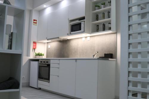 a kitchen with white cabinets and a microwave at Meia Laranja in Almeirim